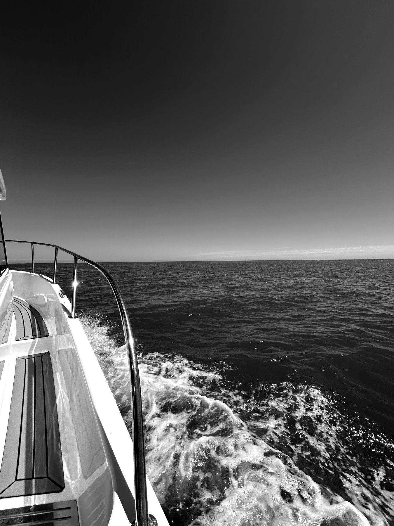 Black and white view of a yacht wake cutting across open sea